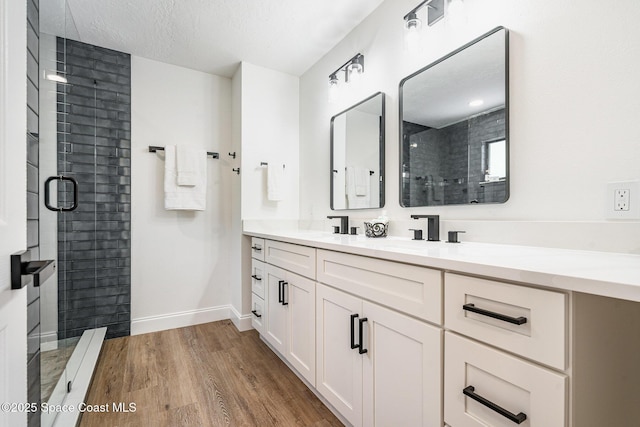 362 Nikomas Way, Melbourne Beach, FL 32951 - bathroom featuring double vanity, wood finished floors, a stall shower, and a textured ceiling