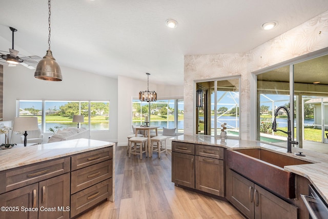 1471 Cypress Trace Dr, Melbourne, FL 32940 - kitchen with stainless steel dishwasher, light wood-type flooring, light stone counters, lofted ceiling, and pendant lighting