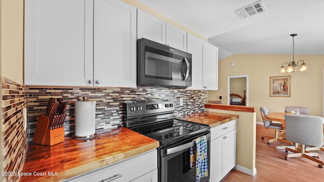 219 Fecco St, Cocoa, FL 32927 - kitchen featuring stainless steel range with electric stovetop, white cabinetry, backsplash, and lofted ceiling