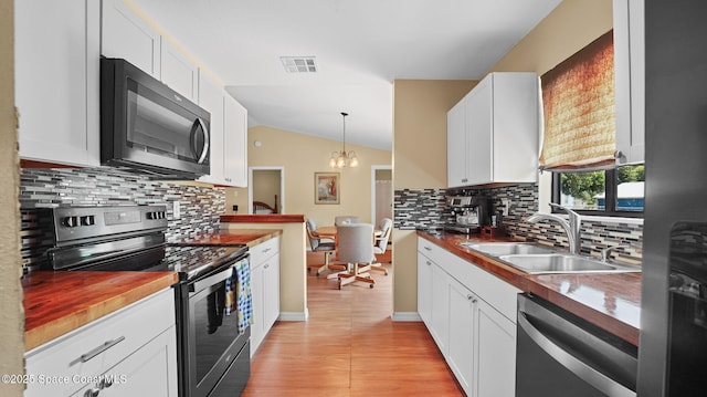 219 Fecco St, Cocoa, FL 32927 - kitchen featuring appliances with stainless steel finishes, vaulted ceiling, tasteful backsplash, white cabinetry, and a chandelier