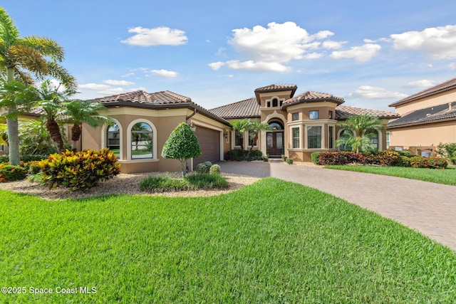 3079 Levanto Dr, Melbourne, FL 32940 - mediterranean / spanish-style home with driveway, a garage, a front lawn, stucco siding, and a tiled roof