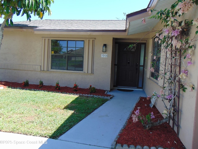 1943 Bradway St NE, Palm Bay, FL 32905 - entrance to property featuring a lawn, stucco siding, and a shingled roof