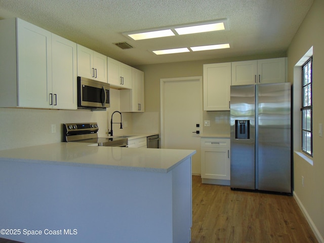 1943 Bradway St NE, Palm Bay, FL 32905 - kitchen with appliances with stainless steel finishes, a peninsula, light countertops, wood finished floors, and a textured ceiling