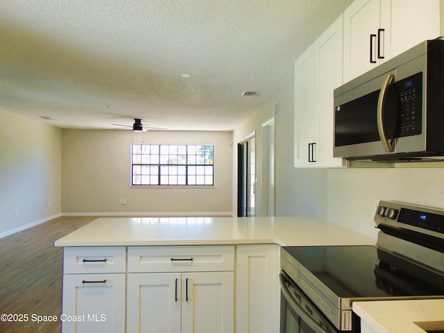 1943 Bradway St NE, Palm Bay, FL 32905 - kitchen featuring stainless steel appliances, a peninsula, a textured ceiling, white cabinets, and wood finished floors