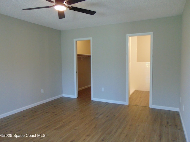 1943 Bradway St NE, Palm Bay, FL 32905 - unfurnished bedroom with a walk in closet, wood finished floors, a closet, ceiling fan, and a textured ceiling