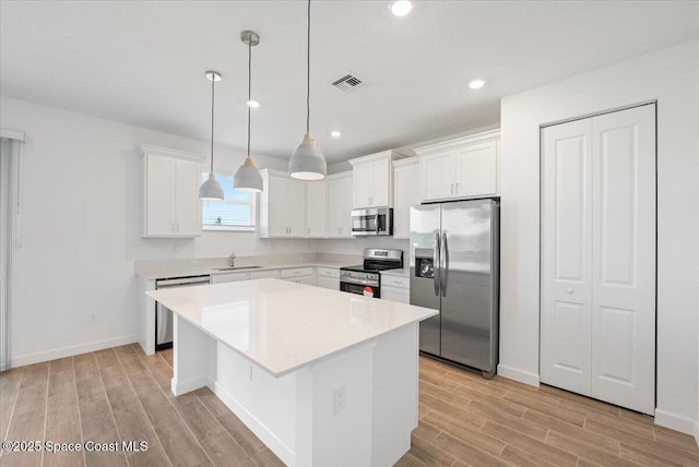 3538 Angler Dr, Ft Pierce, FL 34947 - kitchen featuring appliances with stainless steel finishes, wood tiled floors, a kitchen island, white cabinets, and recessed lighting
