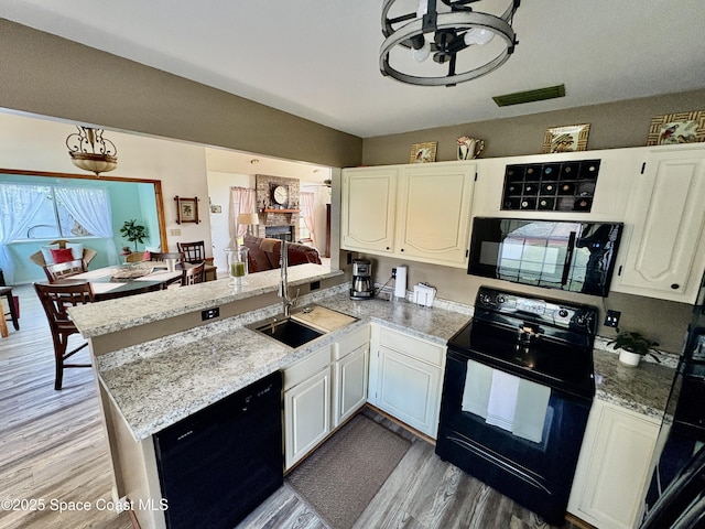 6860 Cairo Rd, Cocoa, FL 32927 - kitchen with black appliances, a peninsula, light wood-type flooring, white cabinets, and light stone counters
