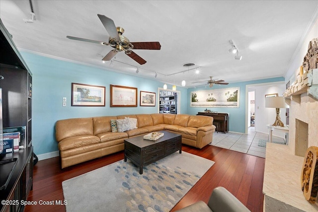 2310 Bignonia St, Melbourne, FL 32901 - living room with ceiling fan, rail lighting, hardwood / wood-style floors, crown molding, and a stone fireplace