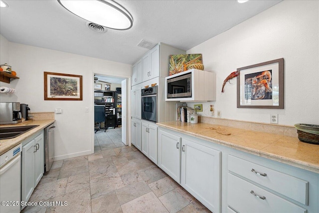 2310 Bignonia St, Melbourne, FL 32901 - kitchen with appliances with stainless steel finishes, stone tile floors, light countertops, an office area, and white cabinets