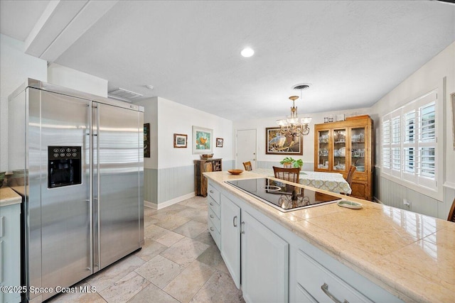 2310 Bignonia St, Melbourne, FL 32901 - kitchen with built in refrigerator, black electric stovetop, stone tile flooring, white cabinets, and a chandelier