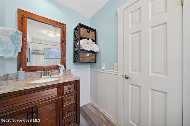 2310 Bignonia St, Melbourne, FL 32901 - full bath with a wainscoted wall, vanity, wood finished floors, and a shower with shower curtain