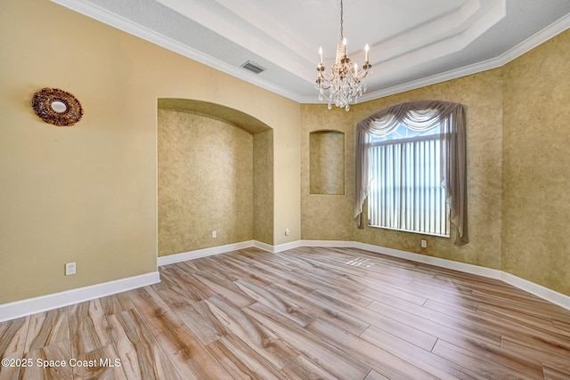 2604 Canary Isles Dr, Melbourne, FL 32901 - empty room with a chandelier, wood finished floors, a raised ceiling, ornamental molding, and arched walkways