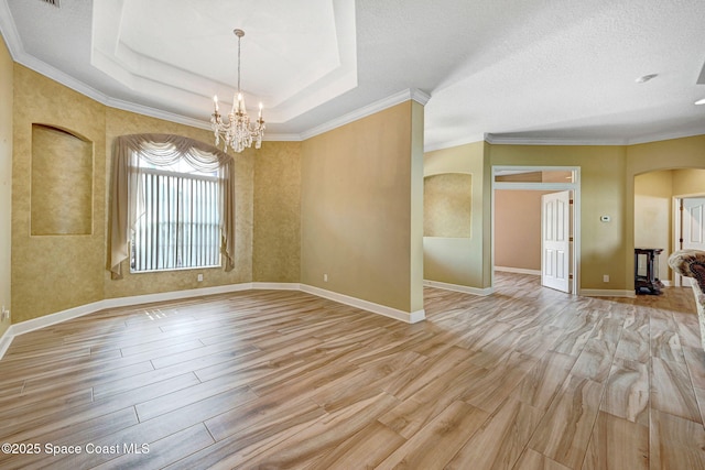 2604 Canary Isles Dr, Melbourne, FL 32901 - unfurnished room featuring arched walkways, a chandelier, light wood finished floors, crown molding, and a raised ceiling