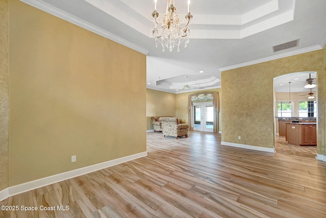 2604 Canary Isles Dr, Melbourne, FL 32901 - unfurnished living room featuring a tray ceiling, ceiling fan, ornamental molding, light wood-style floors, and a chandelier