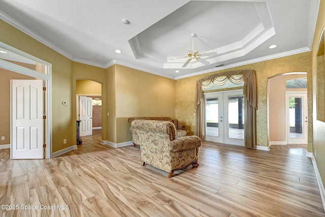 2604 Canary Isles Dr, Melbourne, FL 32901 - living area featuring arched walkways, a raised ceiling, light wood-style flooring, ceiling fan, and french doors