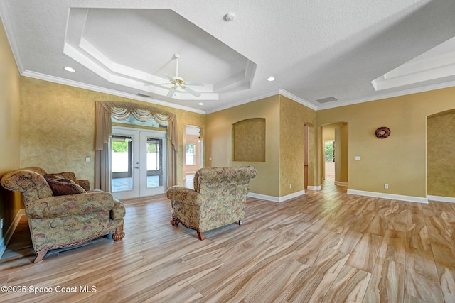 2604 Canary Isles Dr, Melbourne, FL 32901 - living room featuring a raised ceiling, arched walkways, a ceiling fan, ornamental molding, and light wood finished floors