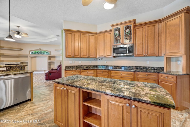 2604 Canary Isles Dr, Melbourne, FL 32901 - kitchen featuring appliances with stainless steel finishes, a ceiling fan, brown cabinets, a textured ceiling, and dark stone counters