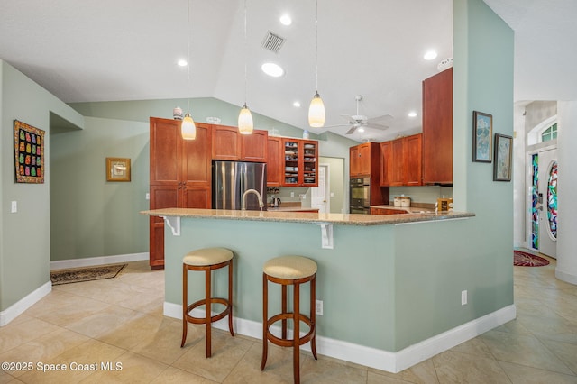 9495 Fleming Grant Rd, Sebastian, FL 32976 - kitchen with freestanding refrigerator, vaulted ceiling, ceiling fan, a breakfast bar, and decorative light fixtures