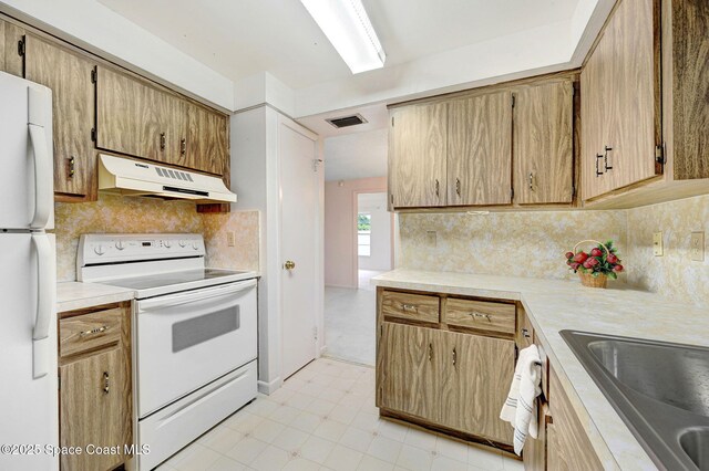 407 Heather Ave NE, Palm Bay, FL 32907 - kitchen with white appliances, under cabinet range hood, decorative backsplash, and light countertops