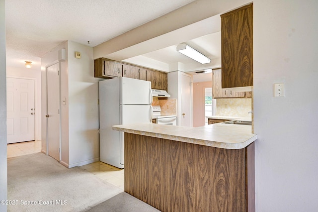407 Heather Ave NE, Palm Bay, FL 32907 - kitchen with under cabinet range hood, white appliances, light countertops, backsplash, and light carpet