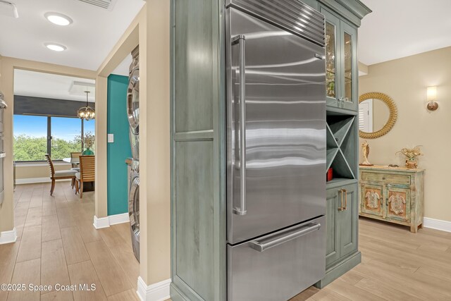 2220 Front St Unit 401, Melbourne, FL 32901 - kitchen with stainless steel built in refrigerator, stacked washer / dryer, light wood-type flooring, glass insert cabinets, and green cabinets