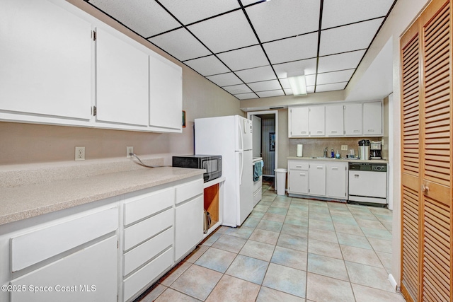 2467 S Washington Ave Unit 103B, Titusville, FL 32780 - kitchen with white appliances, white cabinets, light countertops, light tile patterned floors, and a drop ceiling