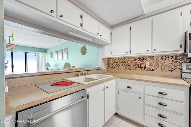 2467 S Washington Ave Unit 103B, Titusville, FL 32780 - kitchen with appliances with stainless steel finishes, tasteful backsplash, white cabinets, and light countertops