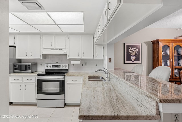840 N Atlantic Ave Unit C103, Cocoa Beach, FL 32931 - kitchen with stainless steel appliances, a peninsula, under cabinet range hood, white cabinets, and light tile patterned flooring