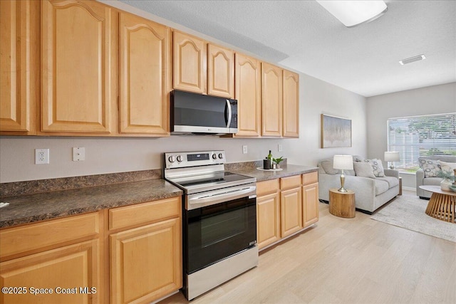 2605 Revolution St Unit 104, Melbourne, FL 32935 - kitchen featuring stainless steel electric stove, light brown cabinetry, light wood-type flooring, dark countertops, and open floor plan