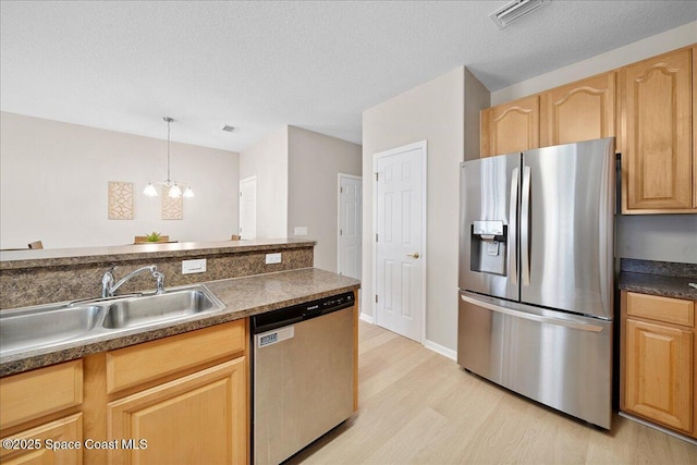 2605 Revolution St Unit 104, Melbourne, FL 32935 - kitchen with appliances with stainless steel finishes, light wood-style flooring, dark countertops, light brown cabinets, and a chandelier
