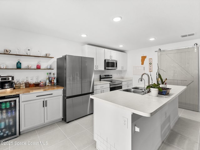 2926 Tishman Rd SE, Palm Bay, FL 32909 - kitchen featuring stainless steel appliances, beverage cooler, a barn door, an island with sink, and light tile patterned floors