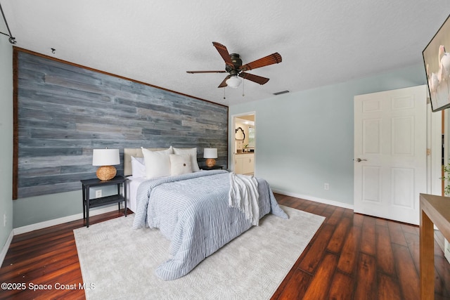 897 Hunters Creek Dr, Melbourne, FL 32904 - bedroom with an accent wall, wood walls, wood finished floors, ceiling fan, and ensuite bath