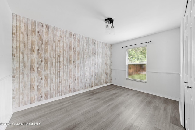 897 Hunters Creek Dr, Melbourne, FL 32904 - empty room featuring wood finished floors, wallpapered walls, and an accent wall