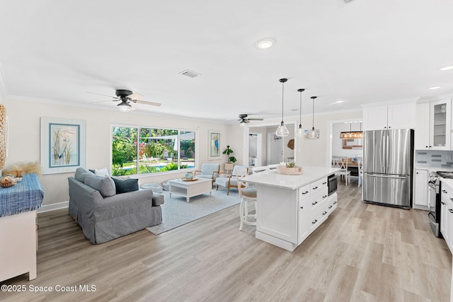 430 Watts Way, Cocoa Beach, FL 32931 - kitchen featuring stainless steel appliances, a ceiling fan, open floor plan, a kitchen breakfast bar, and ornamental molding