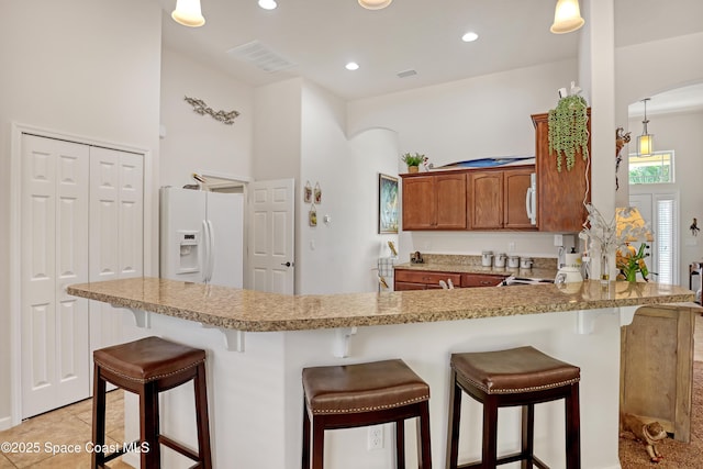143 Sanibel Way, Melbourne Beach, FL 32951 - kitchen with white fridge with ice dispenser, brown cabinets, arched walkways, a peninsula, and a kitchen breakfast bar