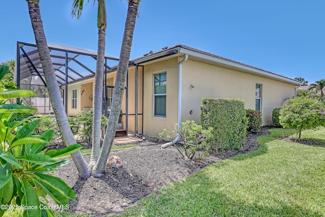 143 Sanibel Way, Melbourne Beach, FL 32951 - view of side of home with stucco siding, a lawn, and glass enclosure