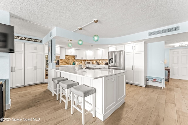 2815 S Atlantic Ave Unit 606, Cocoa Beach, FL 32931 - kitchen featuring appliances with stainless steel finishes, a textured ceiling, white cabinets, light wood-type flooring, and light countertops