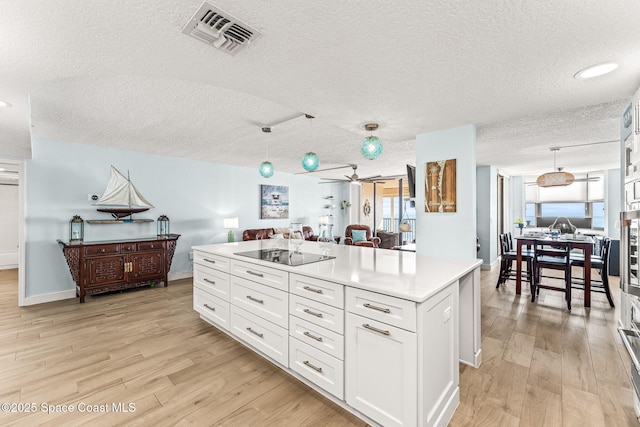 2815 S Atlantic Ave Unit 606, Cocoa Beach, FL 32931 - kitchen with black electric cooktop, a textured ceiling, light wood-style flooring, light countertops, and white cabinets
