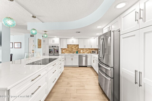 2815 S Atlantic Ave Unit 606, Cocoa Beach, FL 32931 - kitchen featuring stainless steel appliances, white cabinetry, a textured ceiling, light wood-type flooring, and backsplash