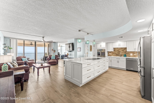 2815 S Atlantic Ave Unit 606, Cocoa Beach, FL 32931 - kitchen featuring open floor plan, appliances with stainless steel finishes, floor to ceiling windows, a textured ceiling, and white cabinets