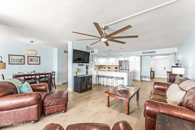 2815 S Atlantic Ave Unit 606, Cocoa Beach, FL 32931 - living area featuring a ceiling fan, light wood-style flooring, and a textured ceiling