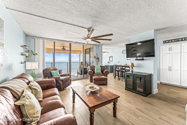 2815 S Atlantic Ave Unit 606, Cocoa Beach, FL 32931 - living room with a wall of windows, a ceiling fan, light wood-style floors, and a textured ceiling