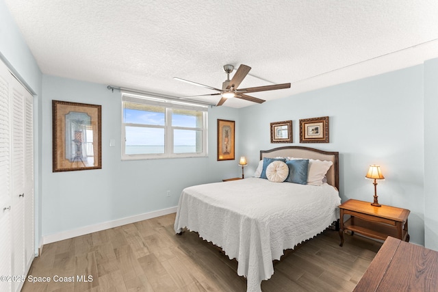 2815 S Atlantic Ave Unit 606, Cocoa Beach, FL 32931 - bedroom featuring light wood-type flooring, a closet, a textured ceiling, and ceiling fan