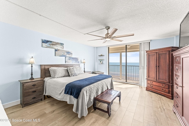 2815 S Atlantic Ave Unit 606, Cocoa Beach, FL 32931 - bedroom with access to outside, a textured ceiling, light wood-style flooring, ceiling fan, and a wall of windows