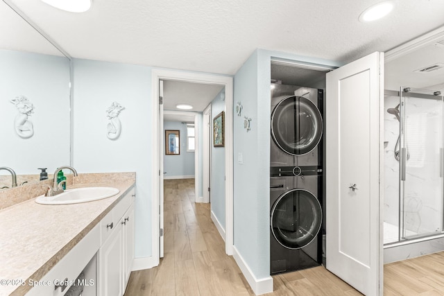2815 S Atlantic Ave Unit 606, Cocoa Beach, FL 32931 - bathroom with stacked washer / drying machine, wood finished floors, a shower stall, vanity, and a textured ceiling