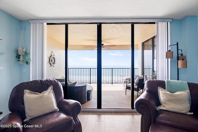 2815 S Atlantic Ave Unit 606, Cocoa Beach, FL 32931 - living room featuring a water view, wood finished floors, expansive windows, ceiling fan, and a textured ceiling