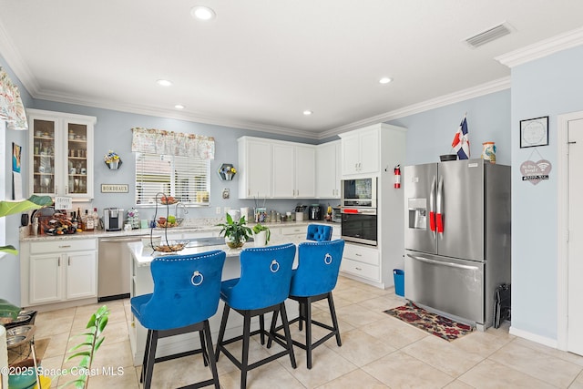 758 Carriage Lake Way, Vero Beach, FL 32968 - kitchen with appliances with stainless steel finishes, ornamental molding, white cabinets, light countertops, and a kitchen island