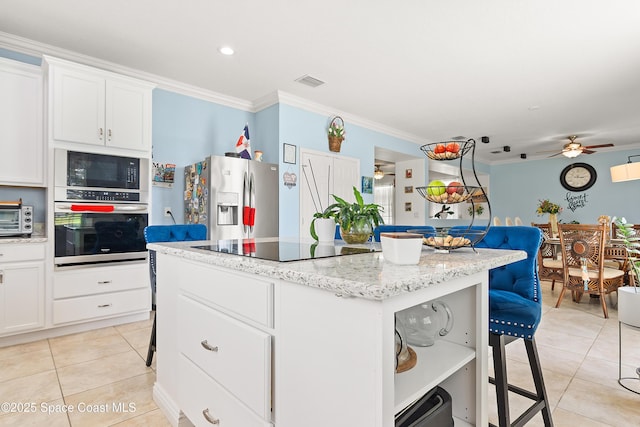 758 Carriage Lake Way, Vero Beach, FL 32968 - kitchen with black appliances, light tile patterned floors, crown molding, a breakfast bar area, and a center island