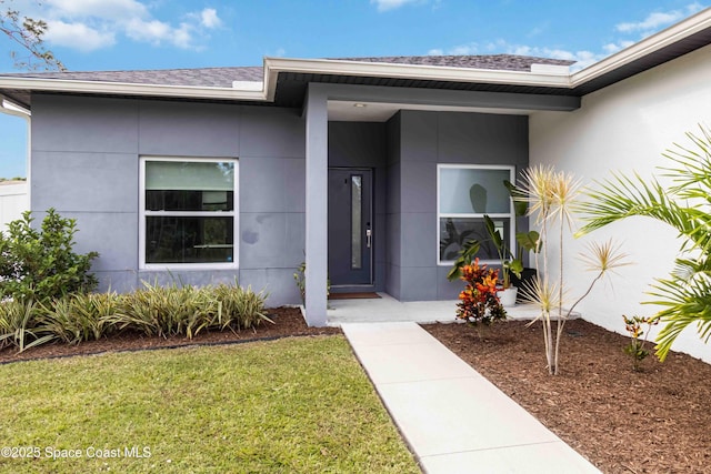2840 Fontainebleau Ave SE, Palm Bay, FL 32909 - view of exterior entry featuring stucco siding, a lawn, and a shingled roof