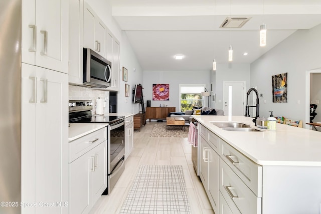 2840 Fontainebleau Ave SE, Palm Bay, FL 32909 - kitchen with stainless steel appliances, light countertops, hanging light fixtures, a kitchen island with sink, and recessed lighting